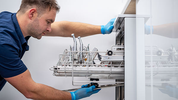 An Eschmann engineer wearing personal protective equipment whilst servicing a washer disinfector